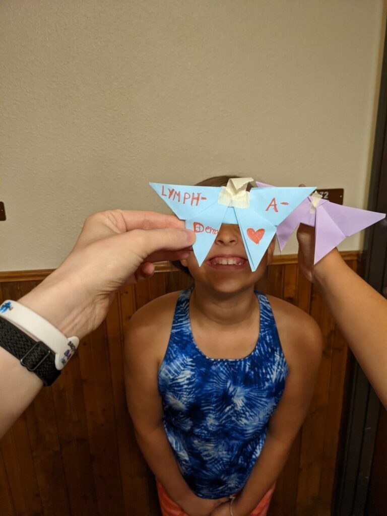 Ruby smiles as Alexa holds a butterfly with the word "Lymphedema" on it over Ruby's face.