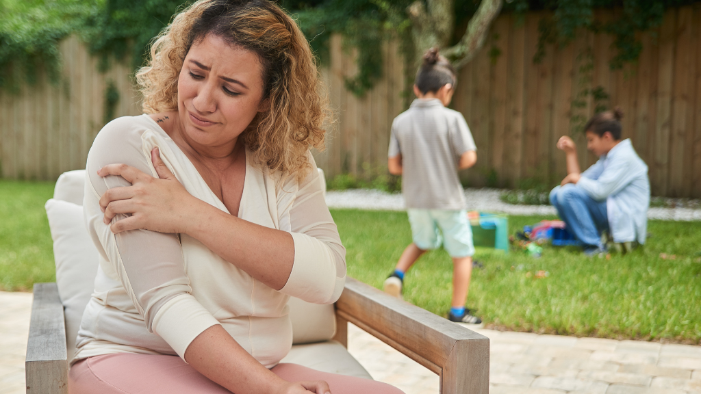 Woman grabbing her right arm with a look of discomfort on her face