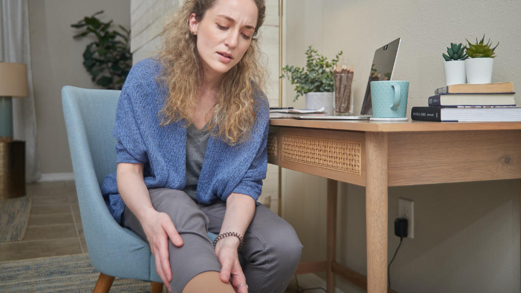 Woman holding her lower leg with a pained expression