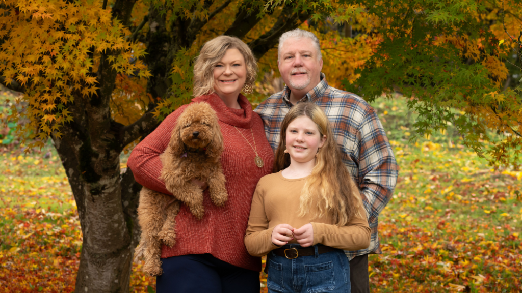 Lisa Duerre, her husband, her daughter, and her dog pose happily for the camera while outside.